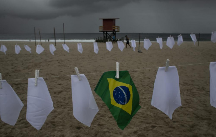 A Brazilian flag hangs on a clothesline on Copacabana beach amid white scarves that represent those who have died of COVID-19 in Rio de Janeiro, Brazil, Friday, Oct. 8, 2021.
