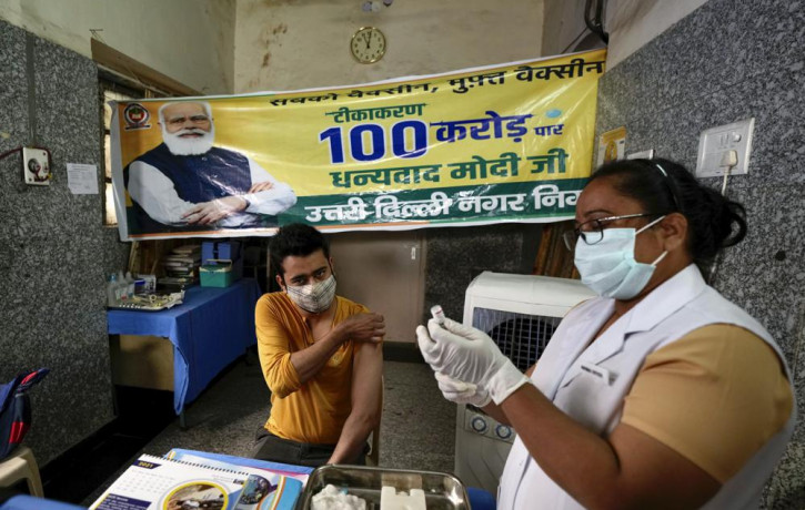 A health worker inoculates a man next to a banner thanking Prime Minister Narendra Modi for 1 billion doses of COVID-19 vaccine at a government hospital in New Delhi, India, Thursday, Oct. 21