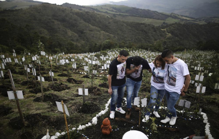 Relatives of Luis Enrique Rodriguez, who died of COVID-19, visit where he was buried on a hill at the El Pajonal de Cogua Natural Reserve, in Cogua, north of Bogota, Colombia, Monday, Oct. 25