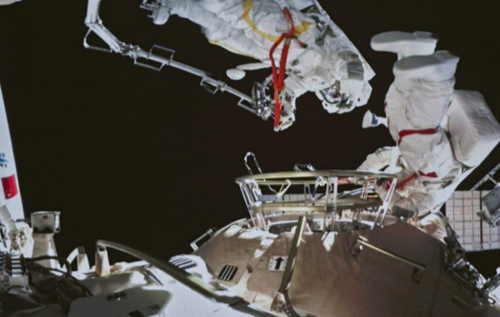 A photo taken on a screen shows Chinese astronauts Zhai Zhigang and Wang Yaping conducting extravehicular activities outside the space station's Tianhe core module, from the Beijing Aerospace