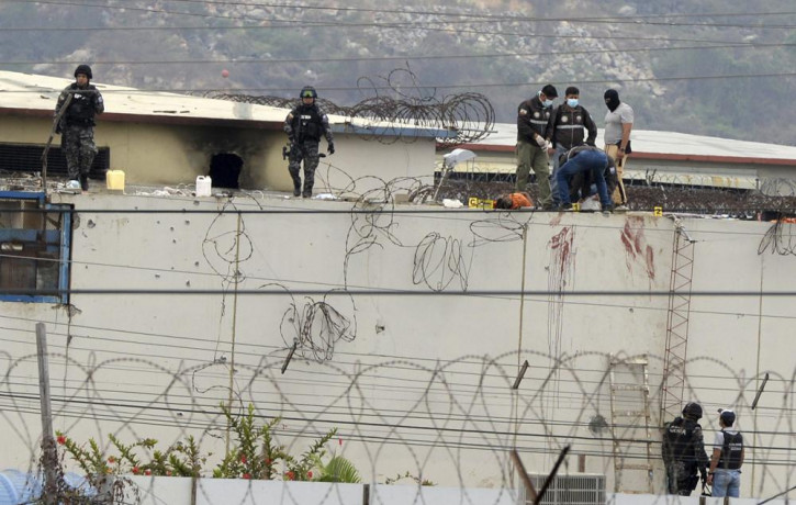 The body of a prisoner appears surrounded by police on the roof of the Litoral penitentiary the morning after riots broke out inside the jail in Guayaquil, Ecuador, Saturday, Nov. 13, 2021.