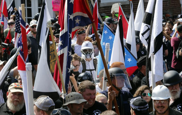 White nationalist demonstrators walk into the entrance of Lee Park surrounded by counter demonstrators in Charlottesville, Va., Saturday, Aug. 12, 2017.