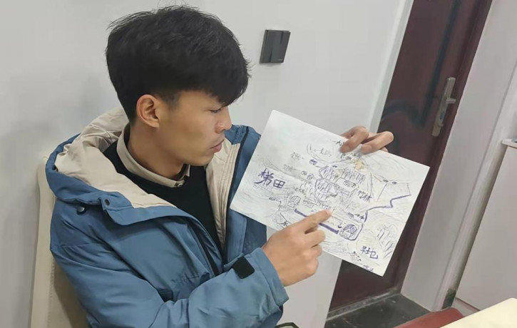 Li Jingwei points to a detail a map he drew from memory of his childhood village as he sits in Lankao in central China's Henan Province, Wednesday, Jan. 5, 2022.
