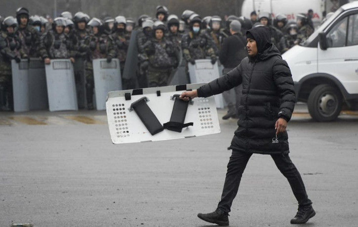 A demonstrator carries a police shield in front of police line during a protest in Almaty, Kazakhstan, Wednesday, Jan. 5, 2022.