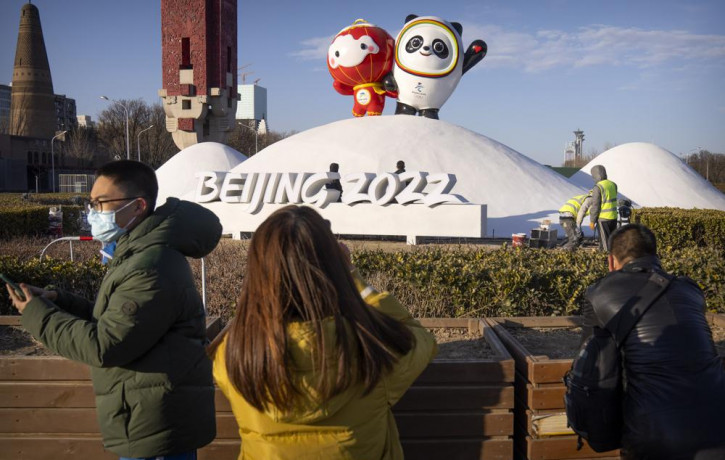 People wearing face masks to help protect against the coronavirus look at a display of the Winter Paralympic mascot Shuey Rhon Rhon, left, and Winter Olympic mascot Bing Dwen Dwen near the Ol