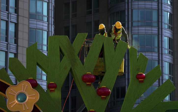 Workers color Chinese Lunar New Year decorations near a commercial office building in Beijing on Sunday, Jan. 16, 2022.