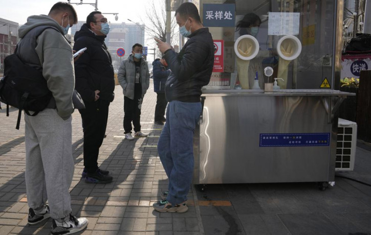 Workers and residents stand near a nuclei test station in Beijing, China, Tuesday, Jan. 18, 2022.