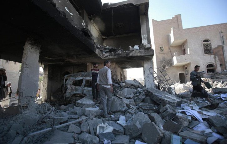 People inspect the wreckage of buildings that were damaged by Saudi-led coalition airstrikes, in Sanaa, Yemen, Tuesday, Jan. 18, 2022.