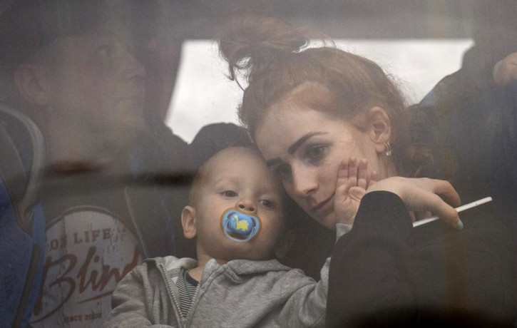 A woman holds her baby inside a bus as they leave Kyiv, Ukraine, Thursday, Feb. 24, 2022.