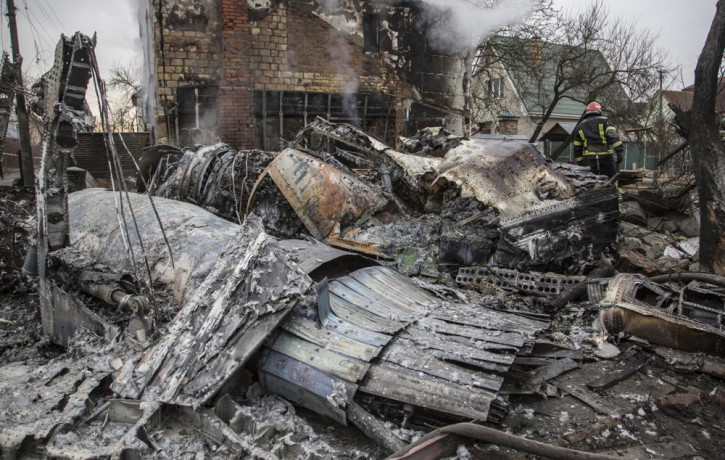 A Ukrainian firefighter walks between at fragments of a downed aircraft seen in in Kyiv, Ukraine, Friday, Feb. 25, 2022.