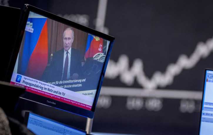 Russia's President Vladimir Putin appears on a television screen at the stock market in Frankfurt, Germany, Feb. 25, 2022.