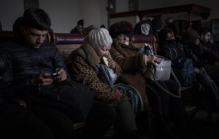 A Ukrainian elderly woman eats a slice of bread inside a crowded Lviv railway station, Monday, Feb. 28, 2022, in Lviv, west Ukraine.