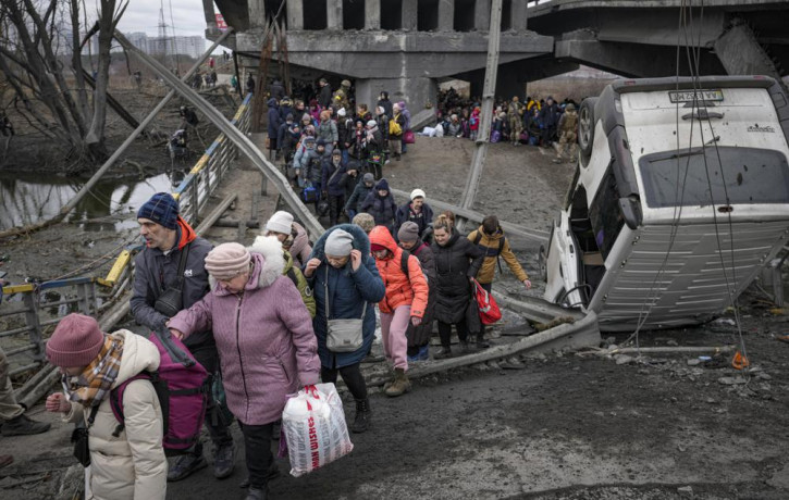 People cross on an improvised path under a bridge that was destroyed by a Russian airstrike, while fleeing the town of Irpin, Ukraine, Saturday, March 5, 2022.