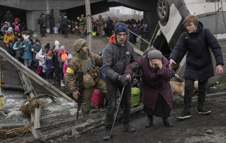 An elderly lady is assisted while crossing the Irpin river, under a bridge that was destroyed by a Russian airstrike, as civilians flee the town of Irpin, Ukraine, Saturday, March 5, 2022.