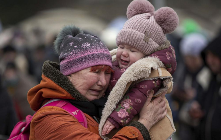 A woman holding a child cries after fleeing from the Ukraine and arriving at the border crossing in Medyka, Poland, Monday, March 7, 2022.