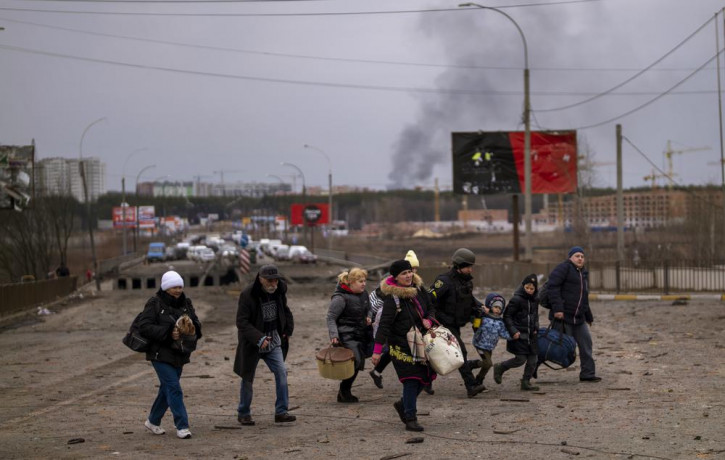 A Ukrainian police officer helps people as artillery echoes nearby while fleeing Irpin in the outskirts of Kyiv, Ukraine, Monday, March 7, 2022.