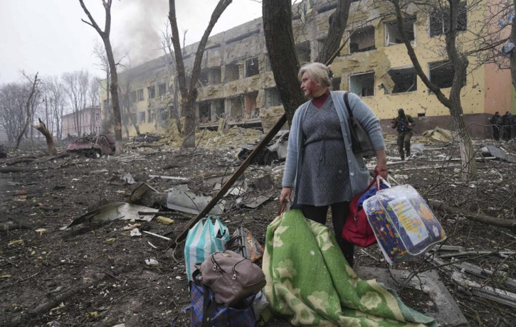A woman walks outside the damaged by shelling maternity hospital in Mariupol, Ukraine, Wednesday, March 9, 2022.