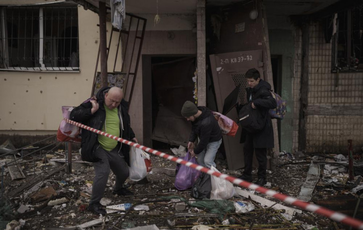 People remove their belongings from a destroyed building after it was hit by artillery shelling in Kyiv in Kyiv, Ukraine, Monday, March 14, 2022.