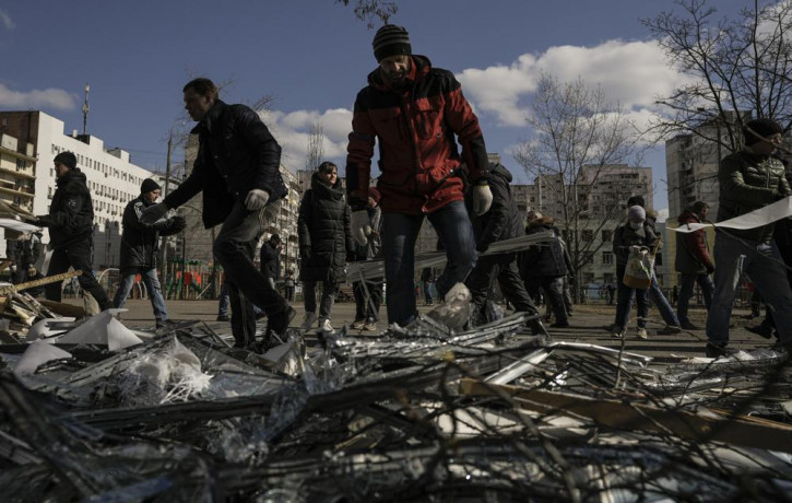 People clear debris outside a medical center damaged after parts of a Russian missile, shot down by Ukrainian air defense, landed on a nearby apartment block, according to authorities, in Kyi