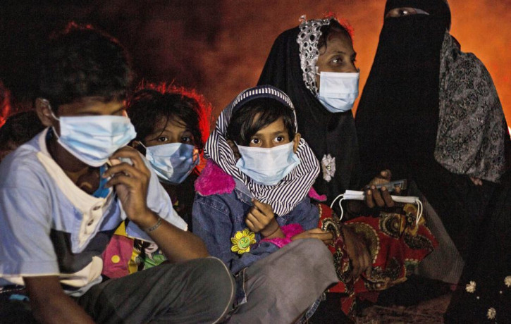 Ethnic Rohingya women and children sit by a fire on a beach after their boat was stranded on Idaman Island in East Aceh, Indonesia, late Friday, June 4, 2021, after leaving a refugee camp in 