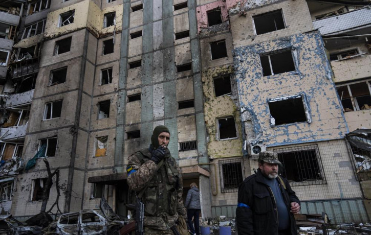 A soldier smokes a cigarette while walking next to a destroyed building after a bombing in Satoya neighborhood in Kyiv, Ukraine, Sunday, March 20, 2022.