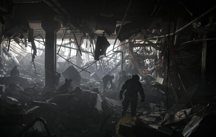 Ukrainian firefighters and servicemen search for people under debris inside a shopping center after bombing in Kyiv, Ukraine, Monday, March 21, 2022.