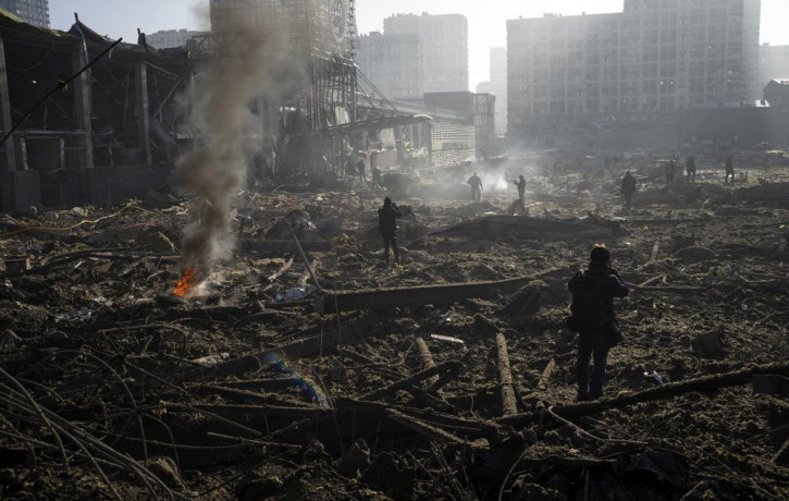 People gather amid the destruction caused after shelling of a shopping center, in Kyiv, Ukraine, Monday, March 21, 2022.