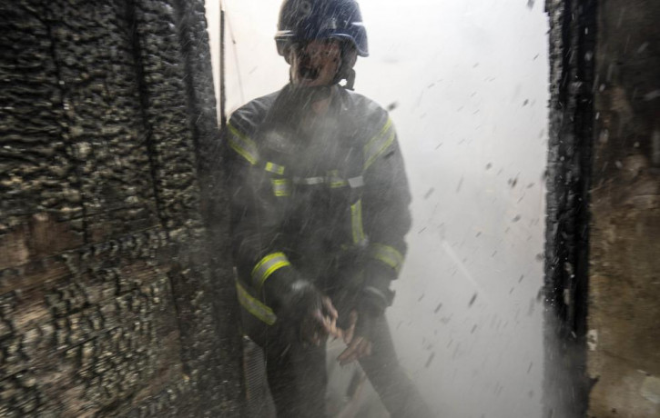 A Ukrainian firefighter shouts to a colleague while trying to extinguish a fire inside a house destroyed by shelling in Kyiv, Ukraine,Wednesday, March 23, 2022.