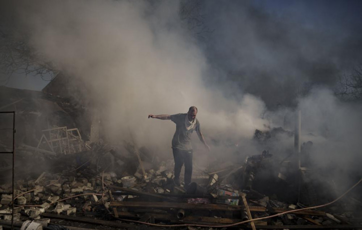 A man walks on the debris of a burning house, destroyed after a Russian attack in Kharkiv, Ukraine, Thursday, March 24, 2022.