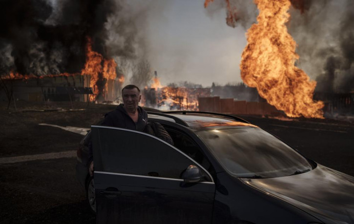 A man enters a car to leave the area of a fire, following a Russian attack in Kharkiv, Ukraine, Friday, March 25, 2022.