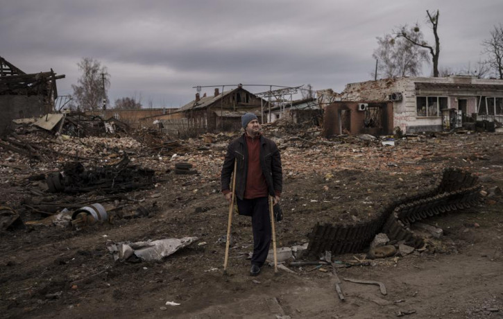 A resident stands next to parts of a destroyed Russian tank in the town of Trostsyanets, Ukraine, Monday, March 28, 2022.