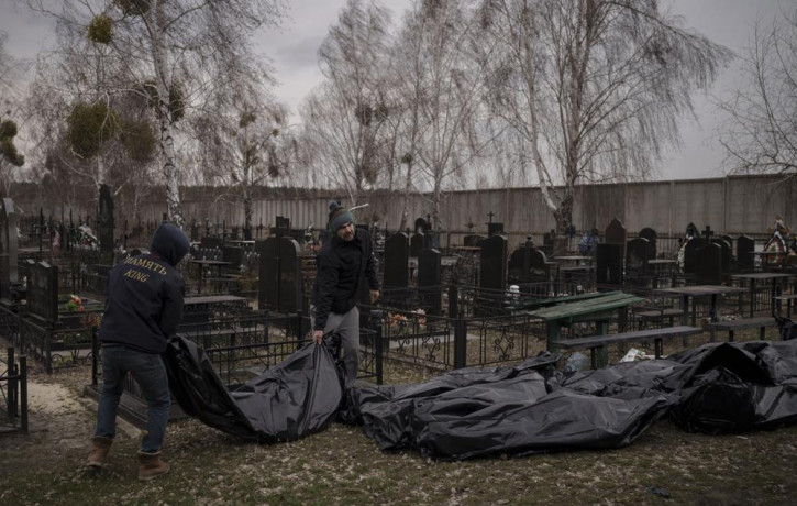 Workers carry the body of people found dead to a cemetery in Bucha, outskirts of Kyiv, Ukraine, Tuesday, April 5, 2022.