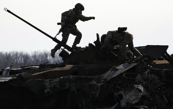 A Ukrainian serviceman walks on a destroyed Russian fighting vehicle in Bucha, Ukraine, Thursday, April 7, 2022.