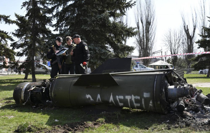 Ukrainian servicemen stand next to a fragment of a Tochka-U missile with a writing in Russian "For children" , on a grass after Russian shelling at the railway station in Kramatorsk, Ukraine,