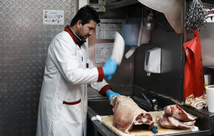 A butcher cuts halal meat in a butcher shop, in Paris, Wednesday, April 13, 2022. Far-right presidential candidate Marine Le Pen is alarming both Muslims and Jews in France with a pledge to b