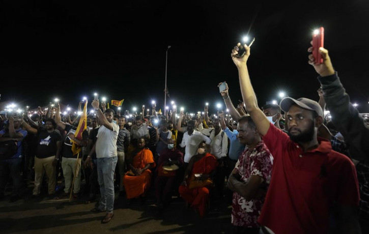 Sri Lankans hold up their mobile phone torches during a vigil condemning police shooting at protesters in Rambukkana, 90 kilometers (55 miles) northeast of Colombo, at a protest outside the p