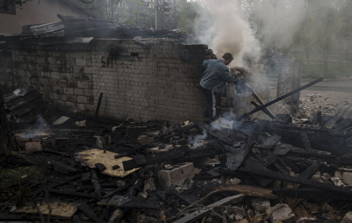 A man tries to extinguish a fire following a Russian bombardment at a residential neighborhood in Kharkiv, Ukraine, Tuesday, April 19, 2022.