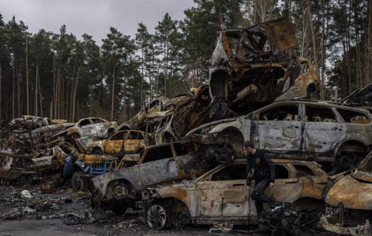 A man walks next a storage place for burned vehicles in Irpin, on the outskirts of Kyiv, Thursday, April 21, 2022.