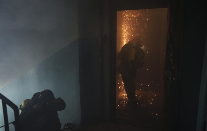 A firefighter opens the door of a burning apartment after a Russian bombardment in Kharkiv, Ukraine, Thursday, April 21, 2022.