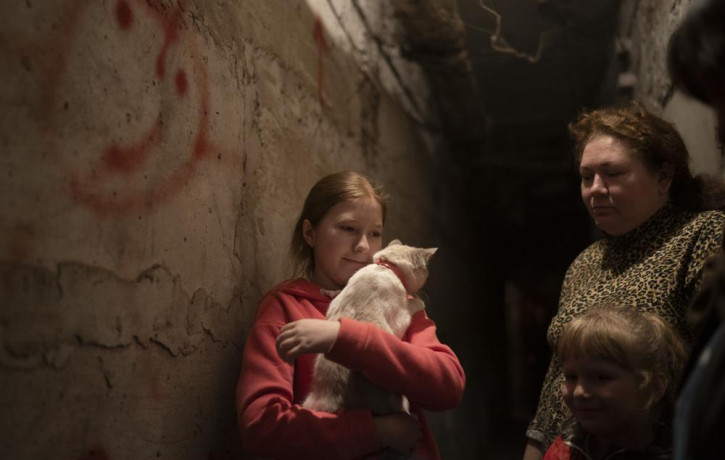 Elizabeth, 12, holds her cat as she takes shelter with her family inside the basement of a residential building during a Russian attack in Lyman, Ukraine, Tuesday, April 26, 2022.