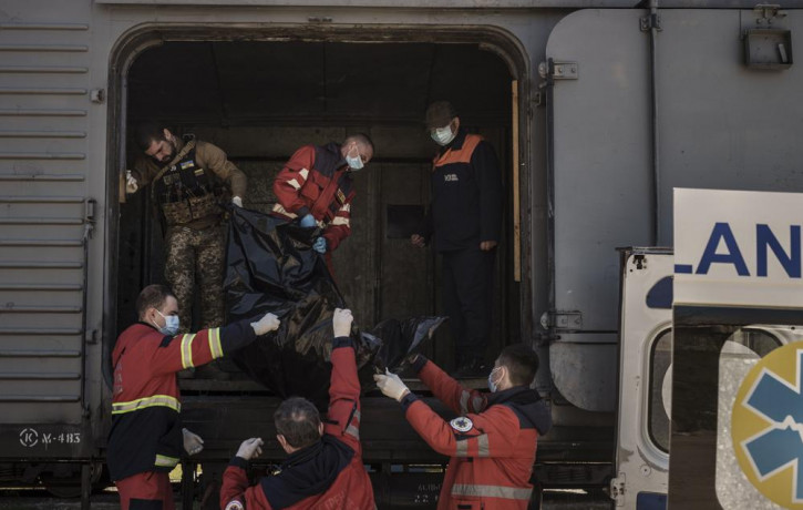 A Ukrainian serviceman and emergency workers carry the body of a Russian soldier into a refrigerated train in Kharkiv, Ukraine, Thursday, May 5, 2022.