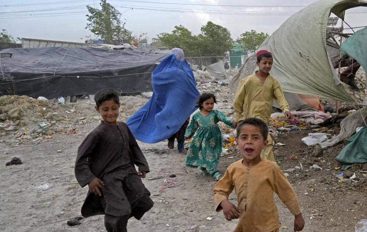 A woman wearing a burka and her children walk in front of their house in Kabul, Afghanistan, Sunday, May 8, 2022.