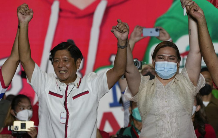 Presidential candidate, Ferdinand Marcos Jr., the son of the late dictator, left, raises arms with running mate Davao City Mayor Sara Duterte, the daughter of the current President, during th