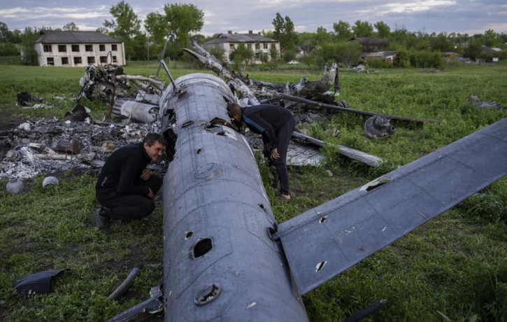 Oleksiy Polyakov, right, and Roman Voitko check the remains of a destroyed Russian helicopter lie in a field in the village of Malaya Rohan, Kharkiv region, Ukraine, Monday, May 16, 2022.