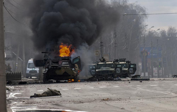 FILE - A Russian armored personnel carrier burns amid damaged and abandoned light utility vehicles after fighting in Kharkiv, the country's second-largest city in Ukraine, Feb. 27, 2022.