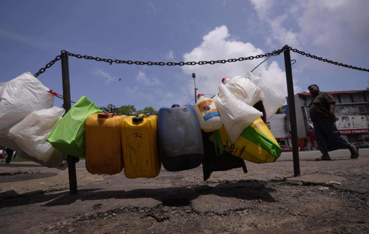 Empty vessels are tied up in a line to secure positions of a queue for buying kerosine oil outside a fuel station in Colombo, Sri Lanka, Sunday, June 5, 2022.