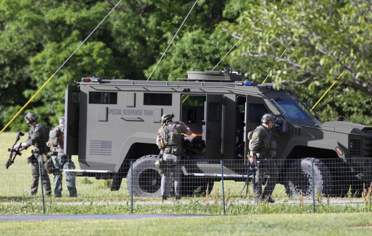 Tactical police work near where a man opened fire at a business, killing three people before the suspect and a state trooper were wounded in a shootout, according to authorities, in Smithsbur