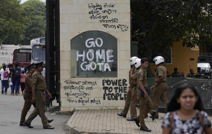 Police officers and people walk past a vandalised entrance to the president's official residence in Colombo, Sri Lanka, Sunday, July 10, 2022. (AP Photo/RSS)