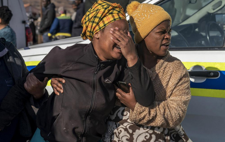 A woman weeps at the scene of an overnight bar shooting in Soweto, South Africa, Sunday July 10, 2022. (AP Photo/RSS)