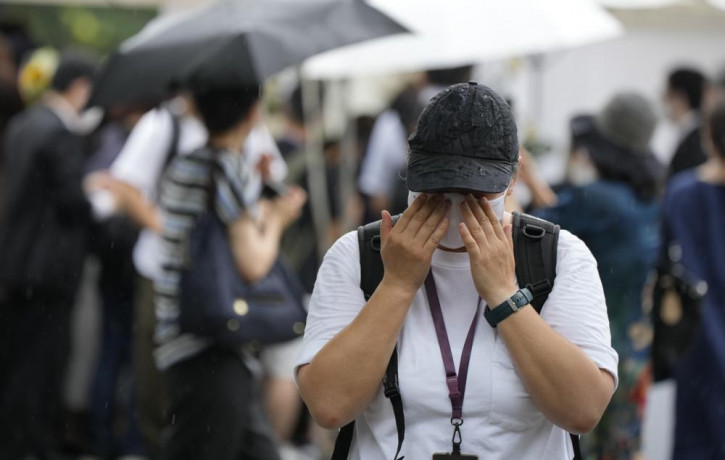 One of people who offer flowers and prayers for former Prime Minister Shinzo Abe, cries at Zojoji temple prior to his funeral wake Tuesday, July 12, 2022, in Tokyo. Abe was assassinated Frida